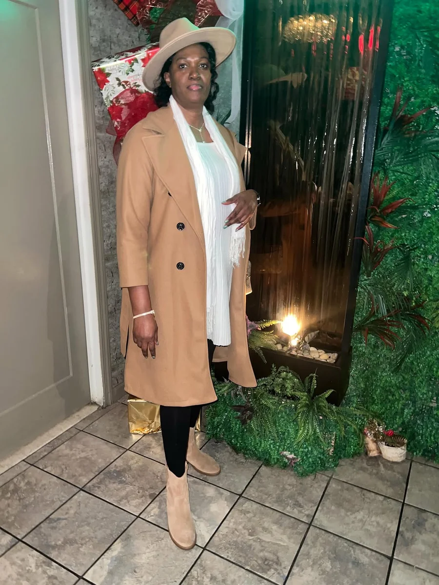 The Holiday-Ready Camel Coat and Beige Boot Combo on a petite woman