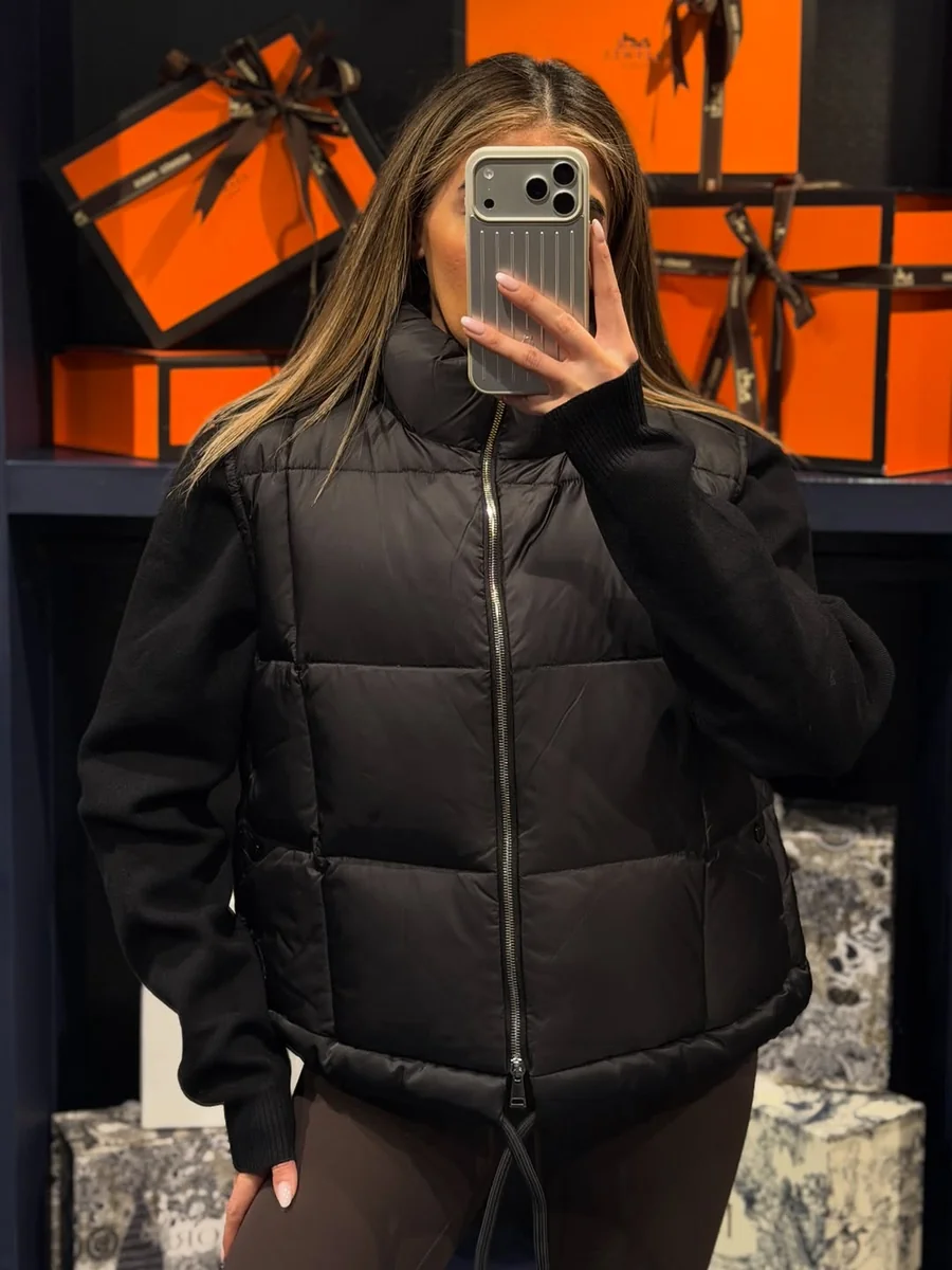 A Black Puffer Vest Over a Black Knit on a petite woman